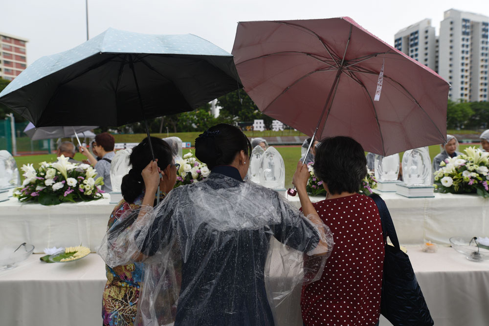 志工为没有穿雨衣的会众撑伞，免受雨淋，安心浴佛。摄 / 黎东兴